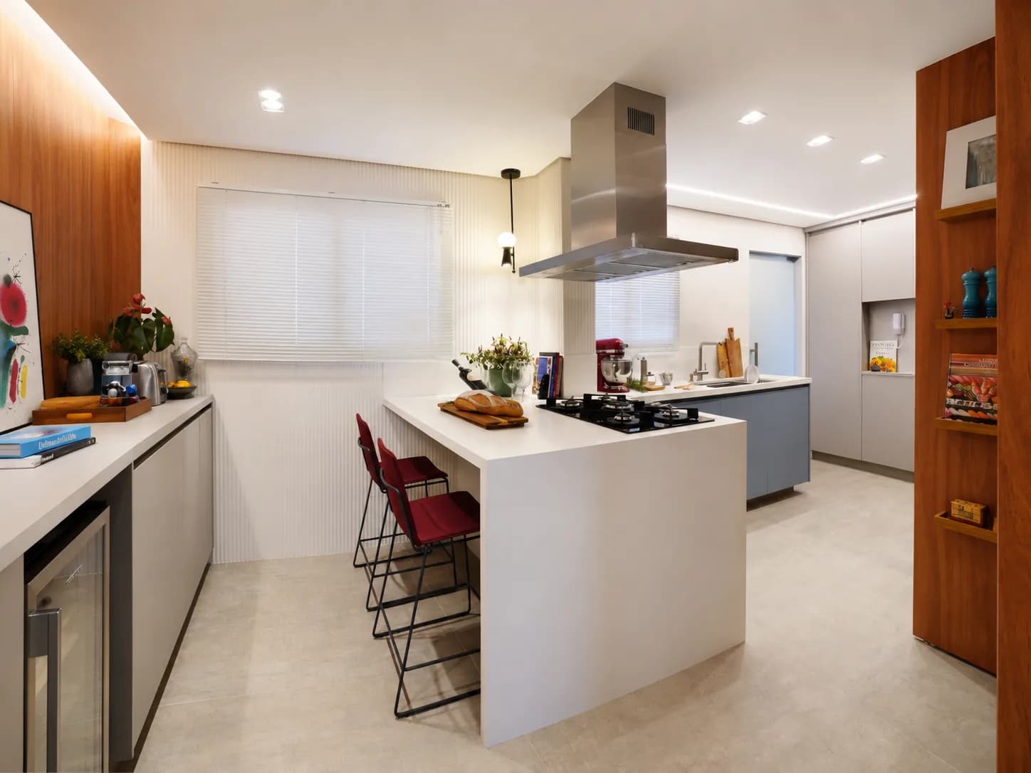 Cozinha com península branca e cooktop, banquetas bordô, coifa de inox e painel de madeira com nichos