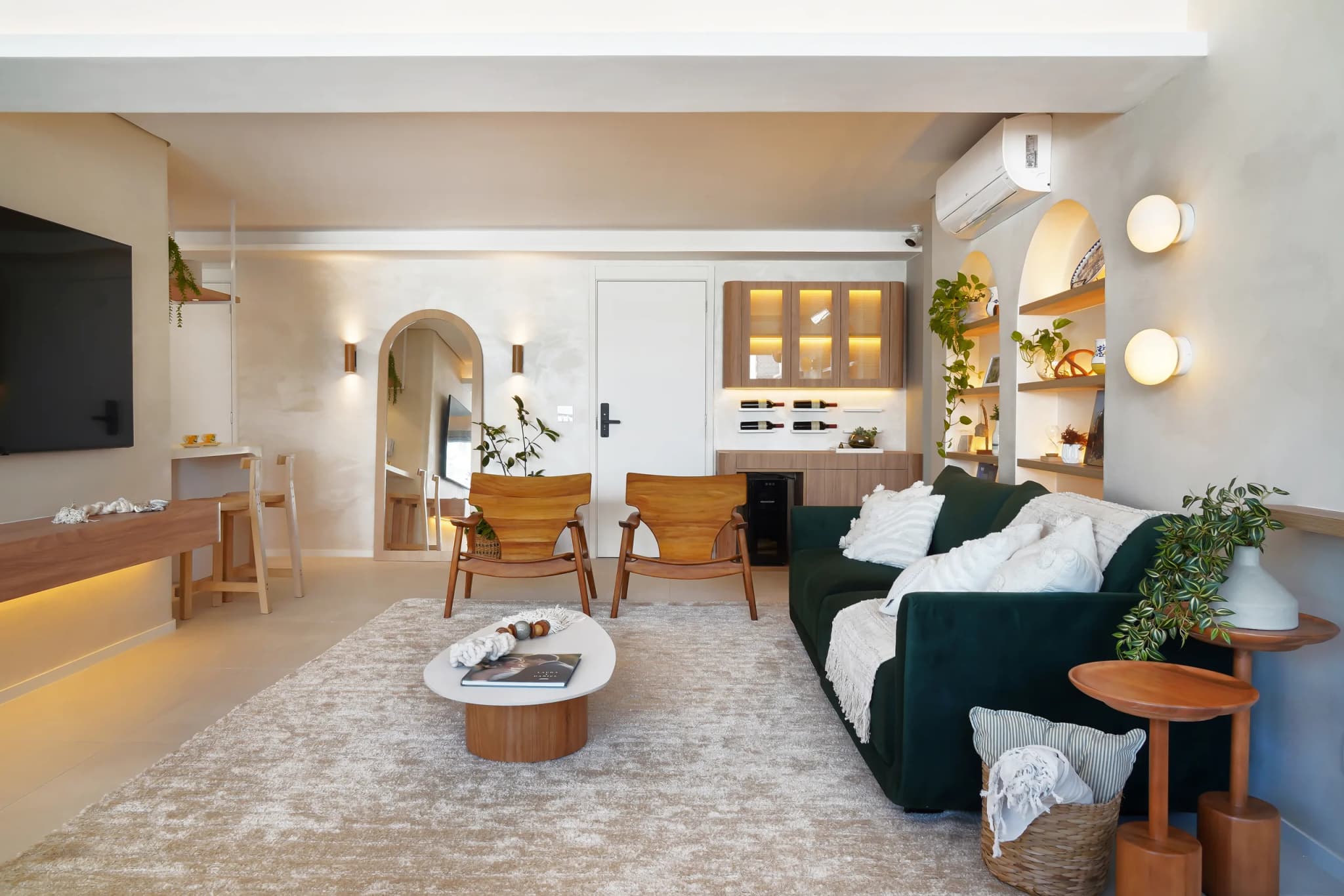 Sala do Apê Colômbia com painel da TV, passagem em arco, sofá verde e mesa de centro redonda