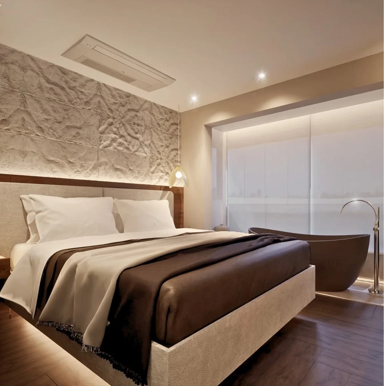 Suíte master com cabeceira de pedra texturizada, roupa de cama em tons de marrom e banheira ao fundo